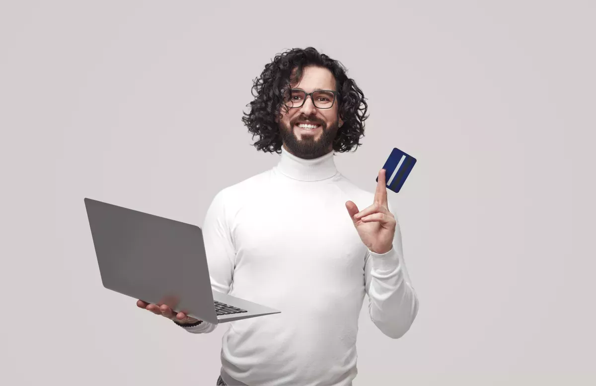 GettyImages-1391504896.jpg Man holding a laptop and debit card