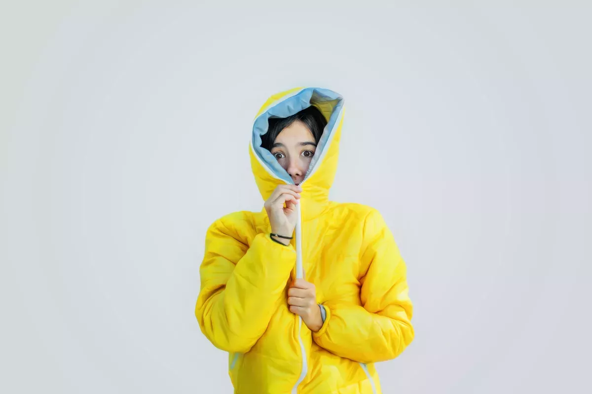GettyImages-587669169_Protect & Comply woman zipping bright yellow jacket up all the way covering mouth