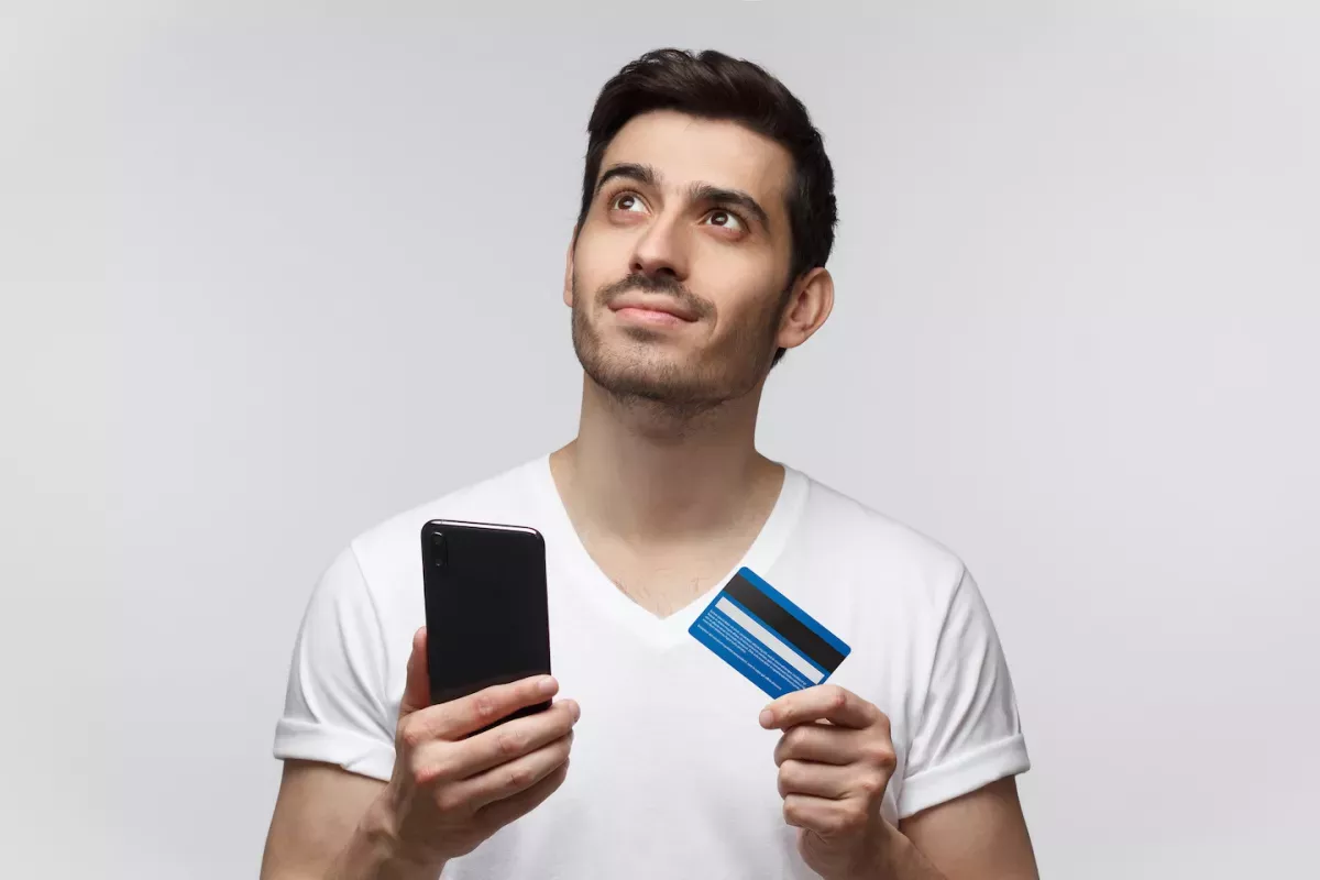 AdobeStock_279505939.jpeg Man holding a phone and credit ard
