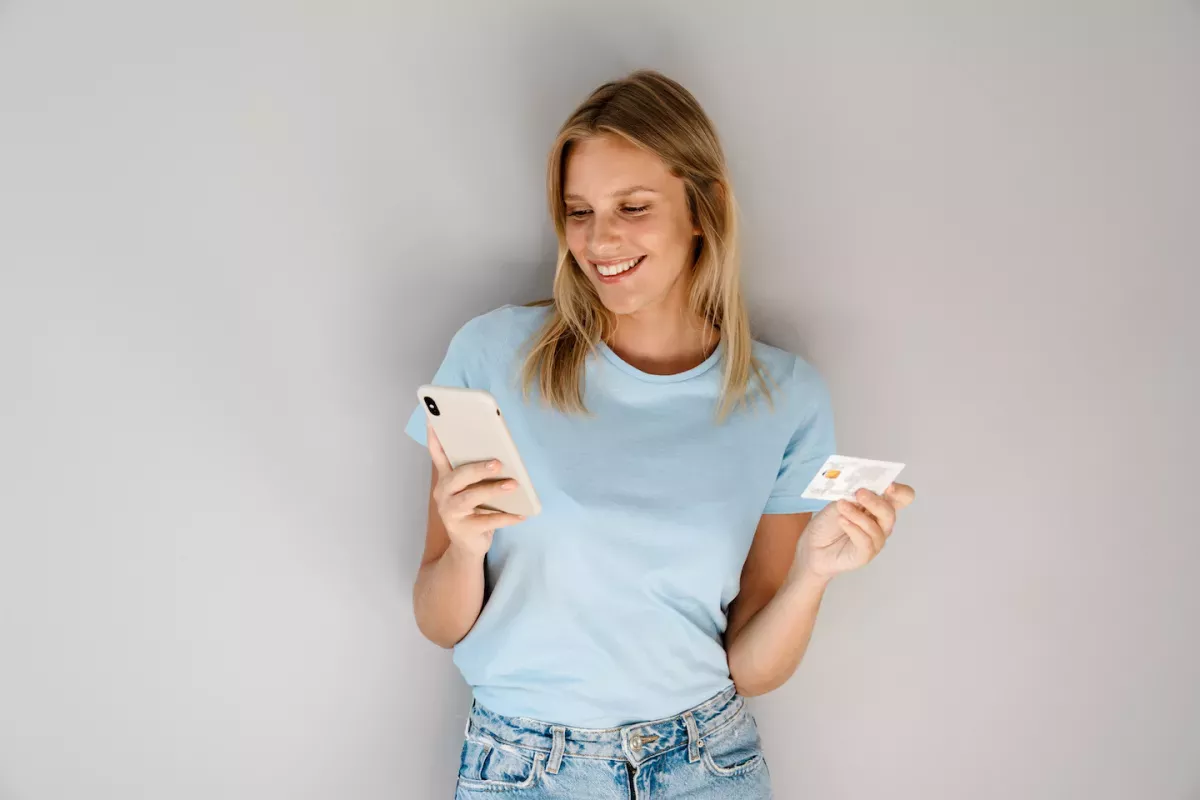 Woman holding a credit card and checking her phone
