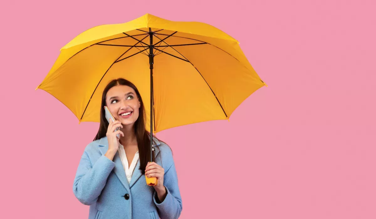 AdobeStock_371978946.jpeg woman on cell phone holding unbrella