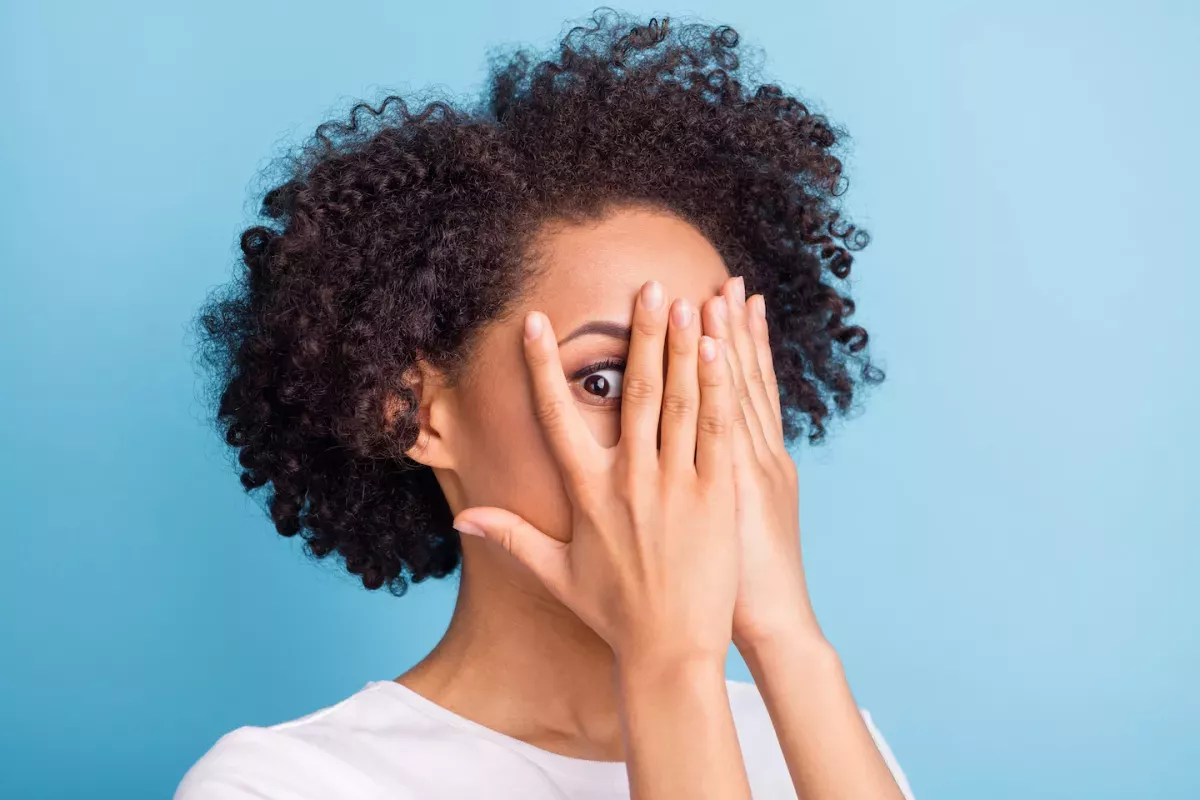 AdobeStock_451231435.jpeg woman hiding face with hands peeking though fingers