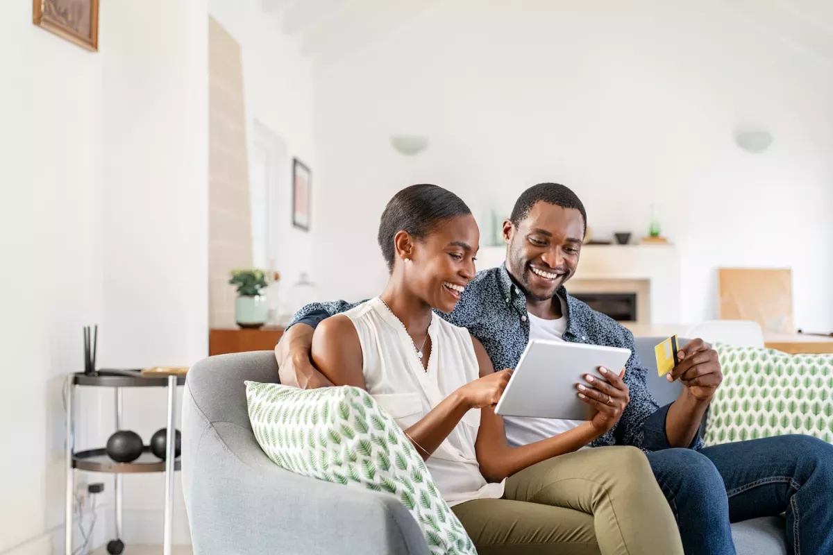 AdobeStock_497313276.jpeg man and woman smiling while using tablet