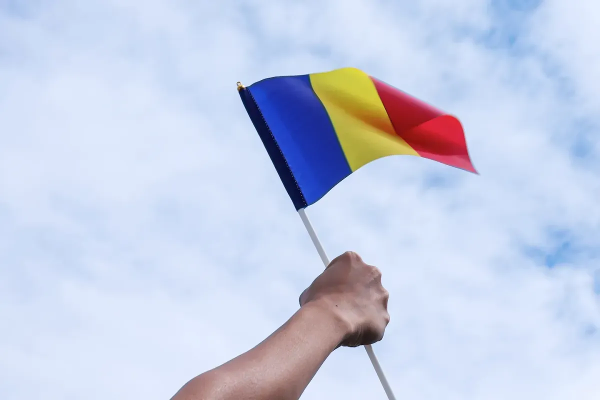 Hand holding Romanian flag in sky Hand holding Romanian flag in sky
