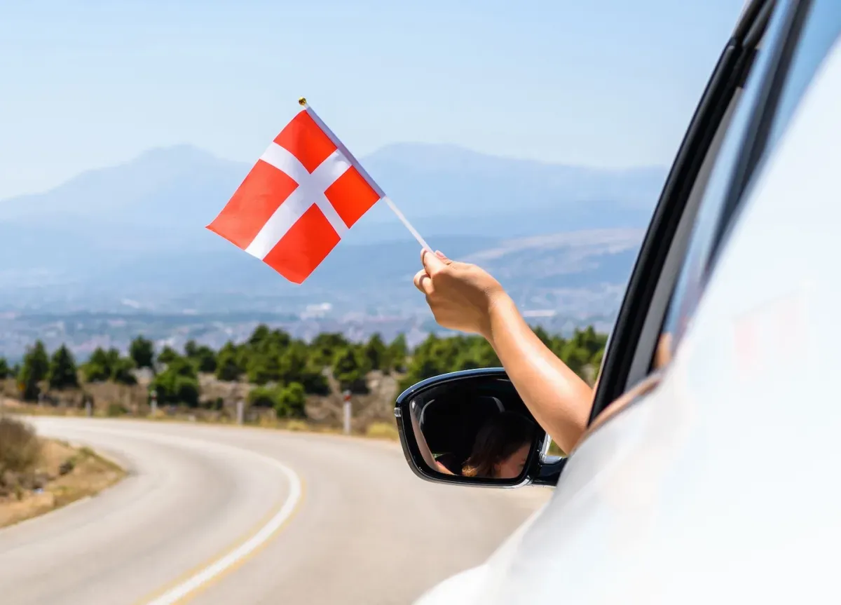 Person holding Denmark flag outside of car window
