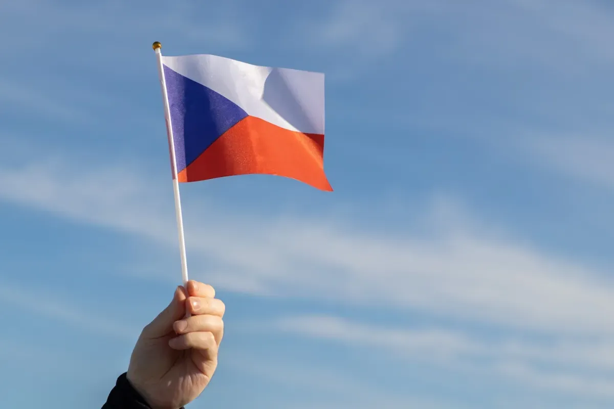 Hand holding Czech Republic flag with blue sky background