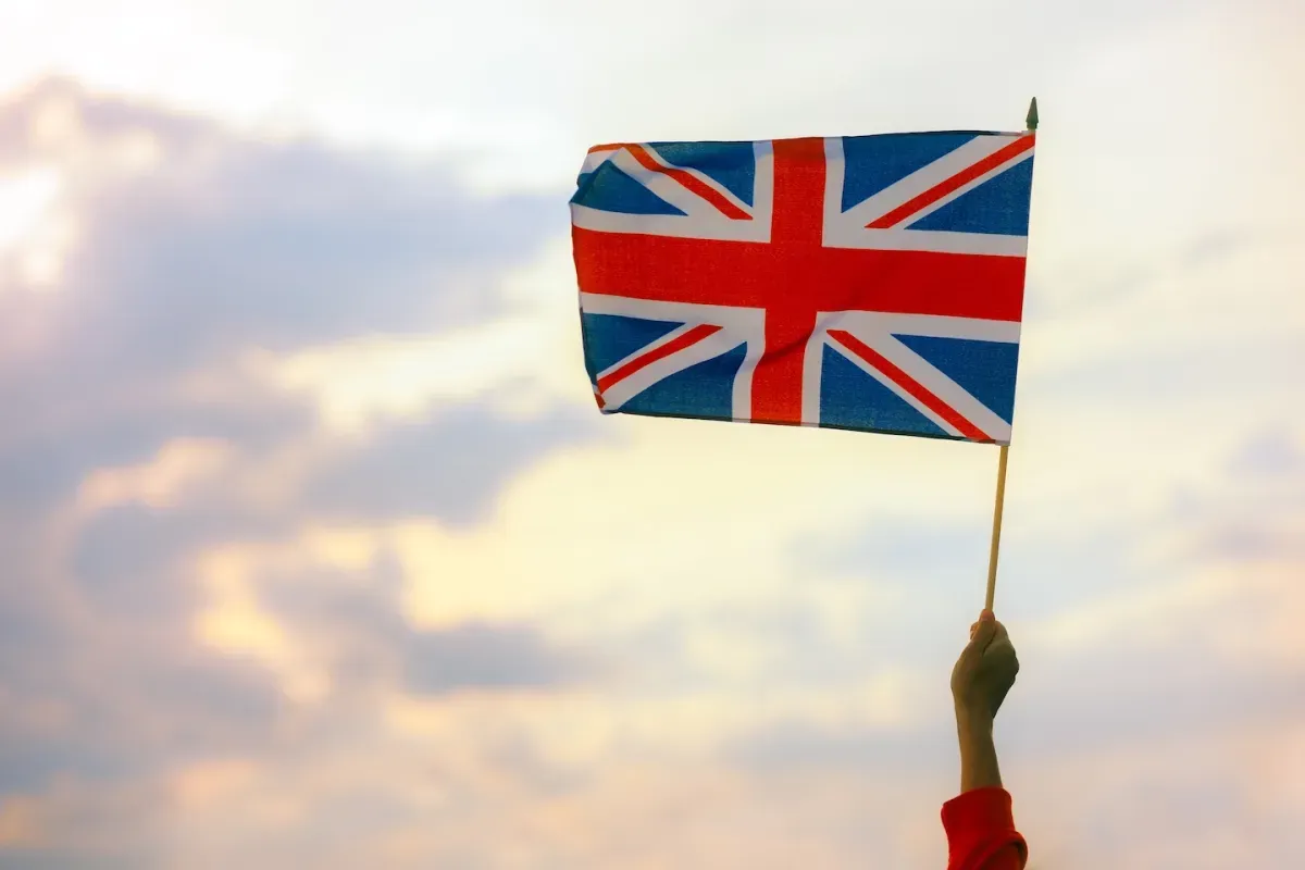 Hand holding UK flag in sky