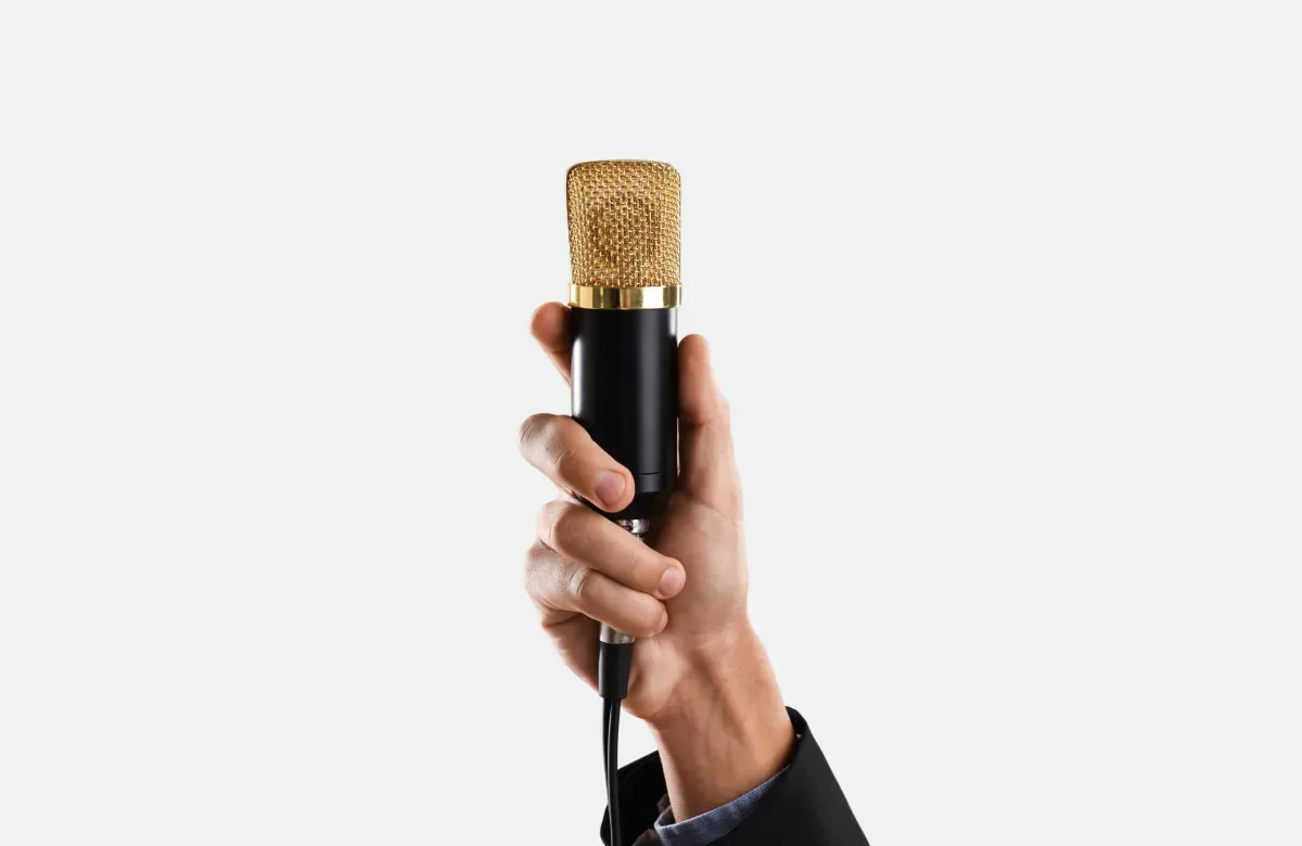 Hand holding a gold and black professional condenser microphone against a white background. Hand holding a gold and black professional condenser microphone against a white background.