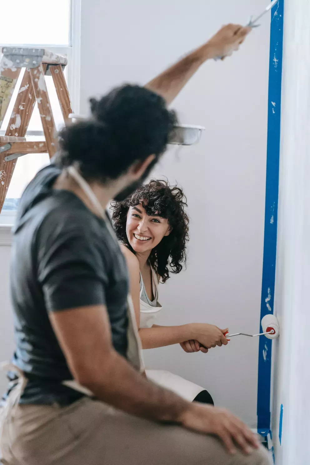 young couple happily painting home together young couple happily painting home together