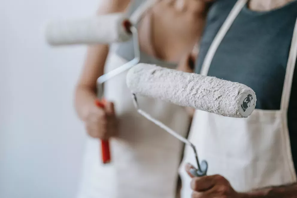 close up of two people holding paint rollers close up of two people holding paint rollers