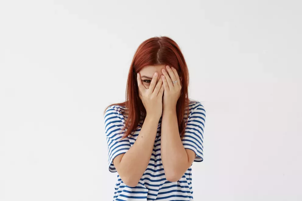 woman hiding behind hands and peeking out of fingers woman hiding behind hands and peeking out of fingers
