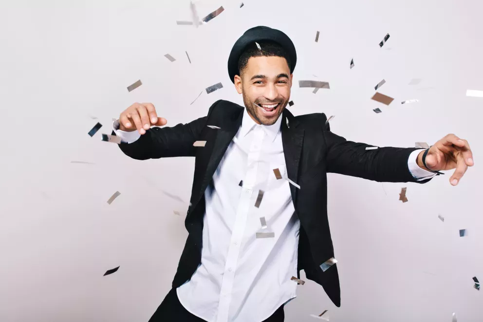 smiling man in suit with party streamers falling all around smiling man in suit with party streamers falling all around