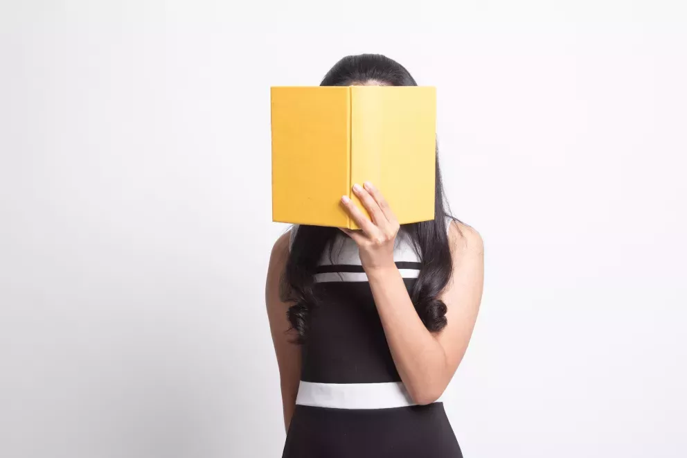 person covering face with big yellow book person covering face with big yellow book