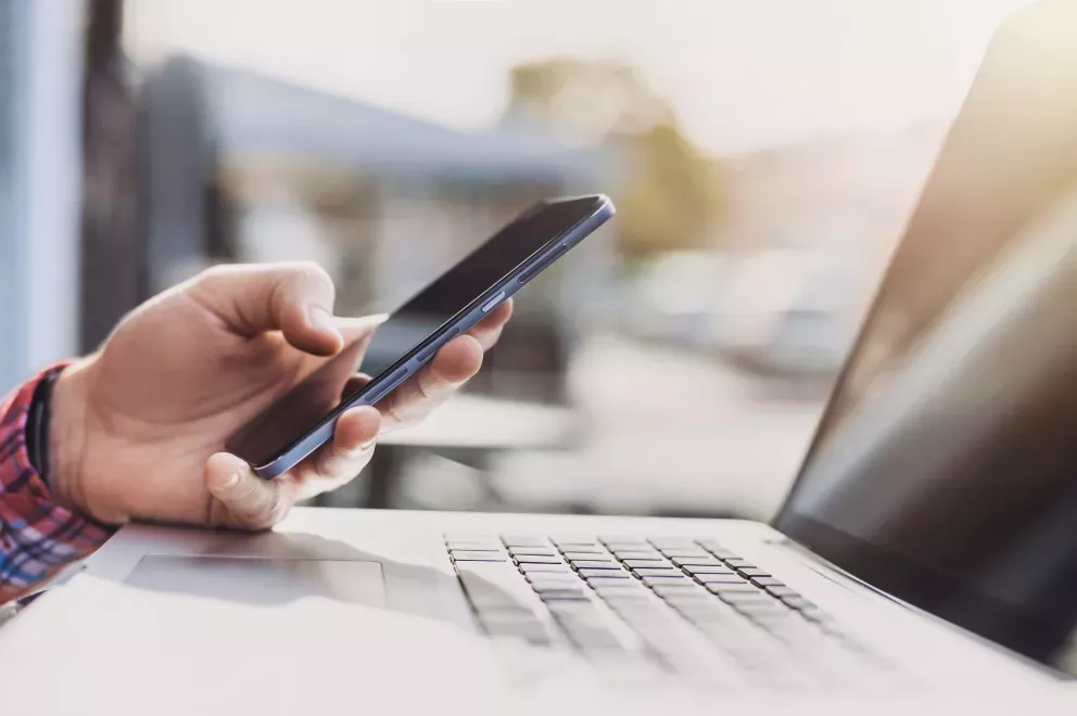 close up of person using cell phone and laptop