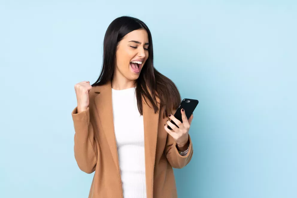 woman looking at cell phone exclaiming with joy woman looking at cell phone exclaiming with joy
