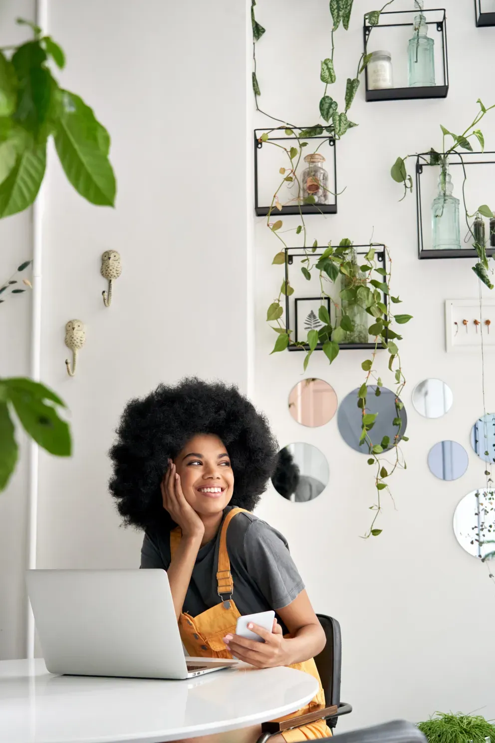 smiling young woman using laptop and cell phone
