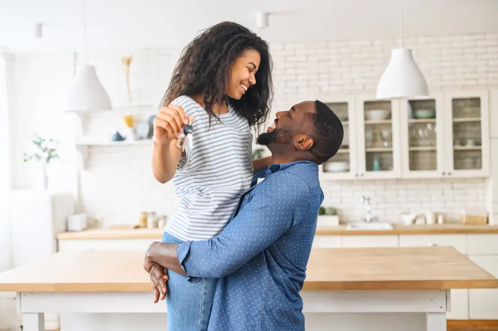 excited couple in new home holding new keys and hugging