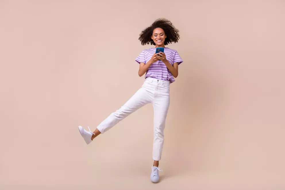 smiling woman jumping with cell phone in hand smiling woman jumping with cell phone in hand