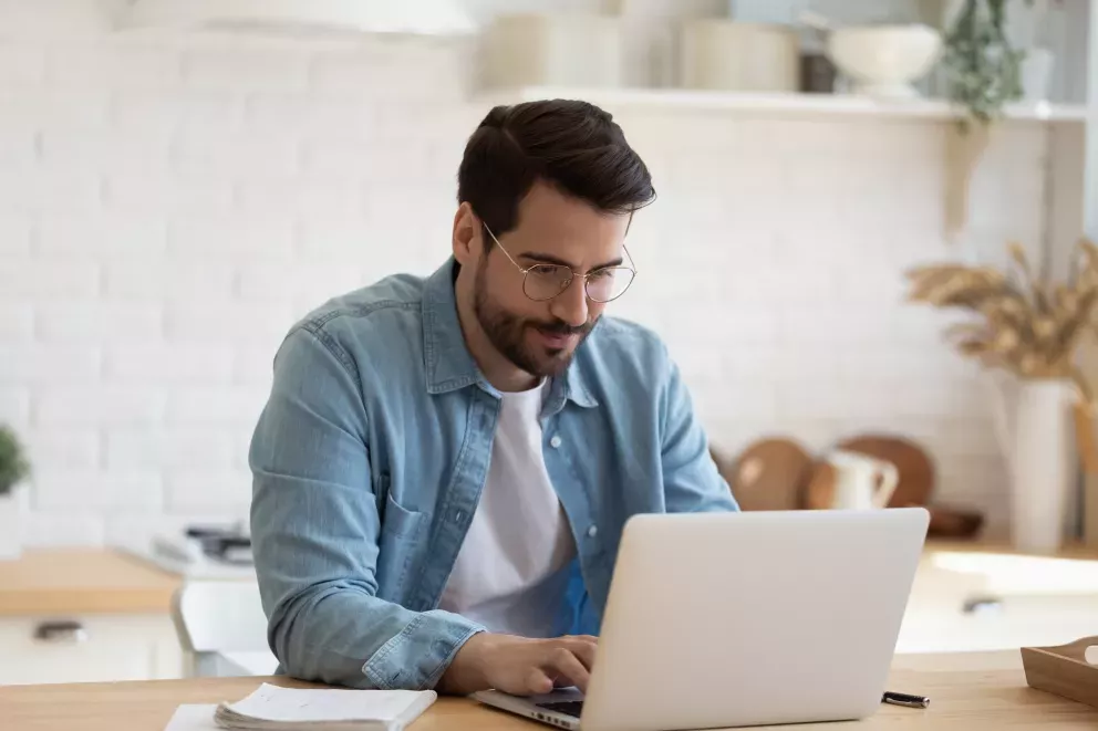 man using laptop on kitchen counter man using laptop on kitchen counter