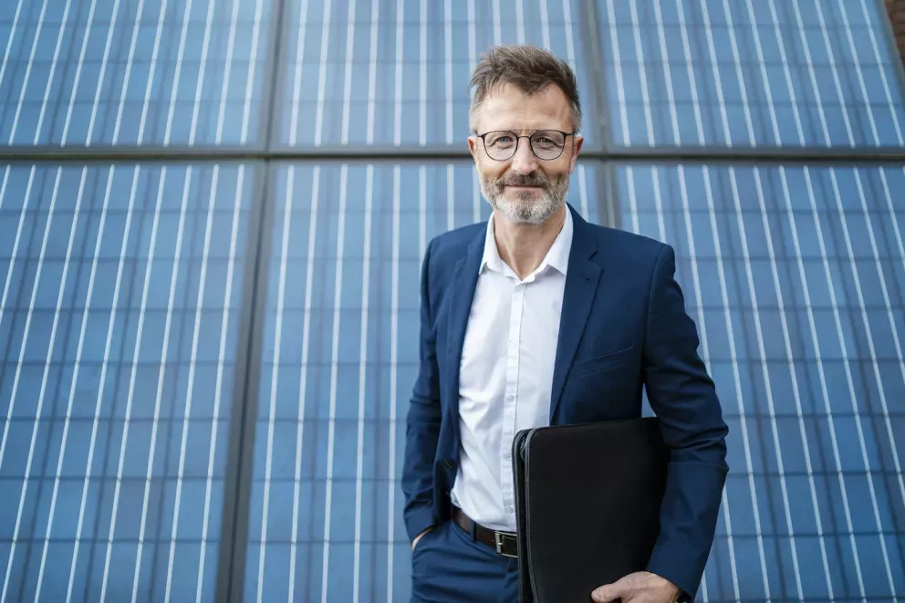 Business man standing by solar panels Business man standing by solar panels