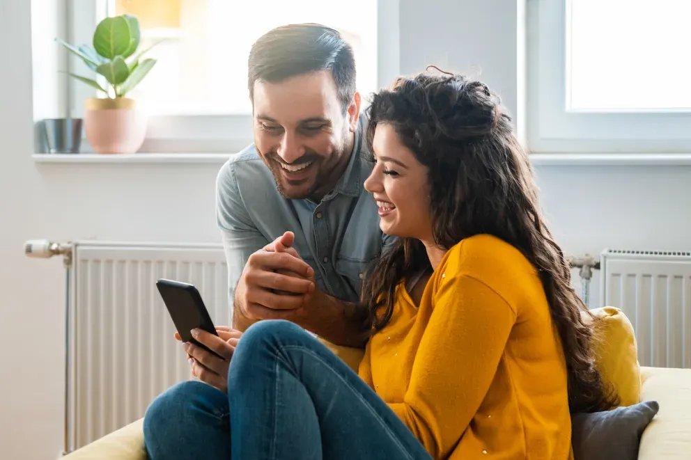 man and woman looking at phone and smiling