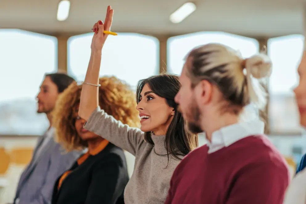 woman raising hand at conference 