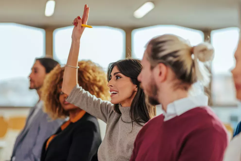 woman raising hand at conference woman raising hand at conference