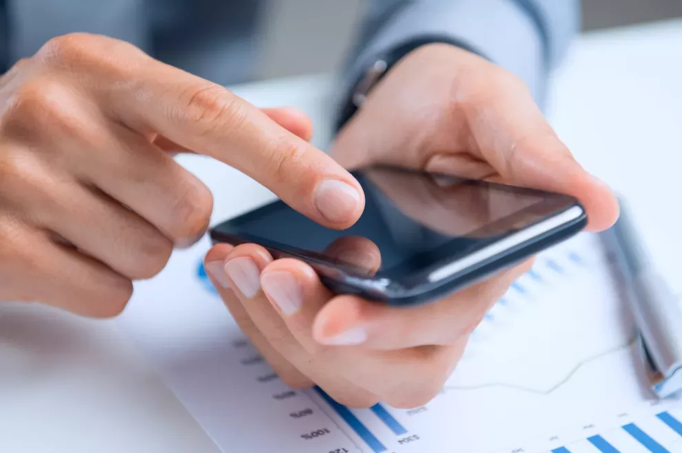 hands using phone with chart underneath hands using phone with chart underneath