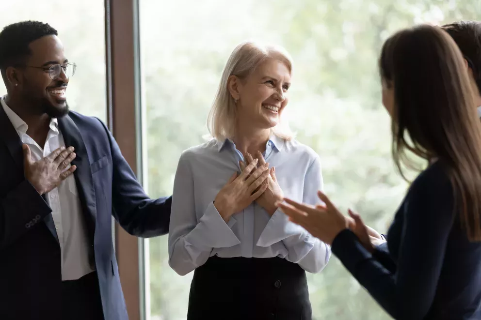 coworkers giving compliment to smiling woman on team coworkers giving compliment to smiling woman on team