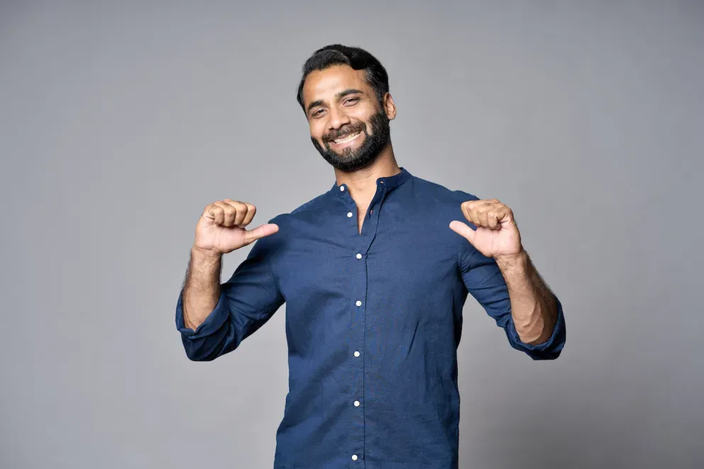 confident person smiling and pointing at self
