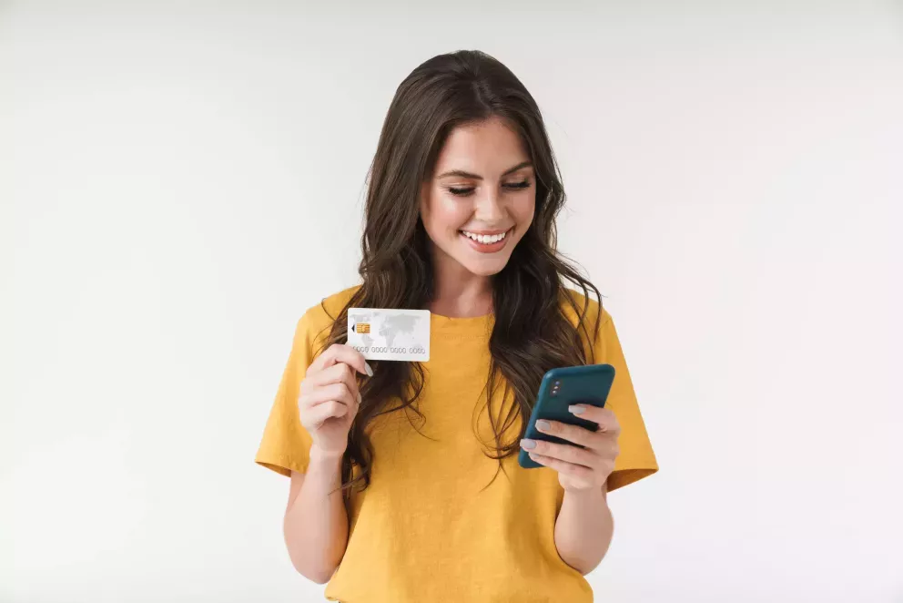 Woman looking at a phone holding a credit card Woman looking at a phone holding a credit card