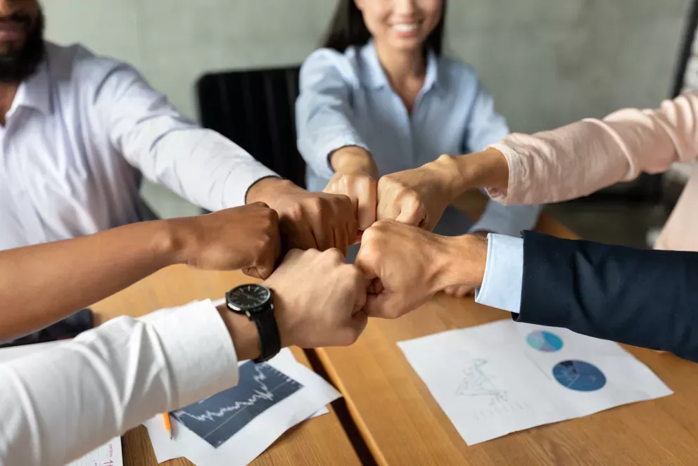 team of coworkers putting fists together team of coworkers putting fists together
