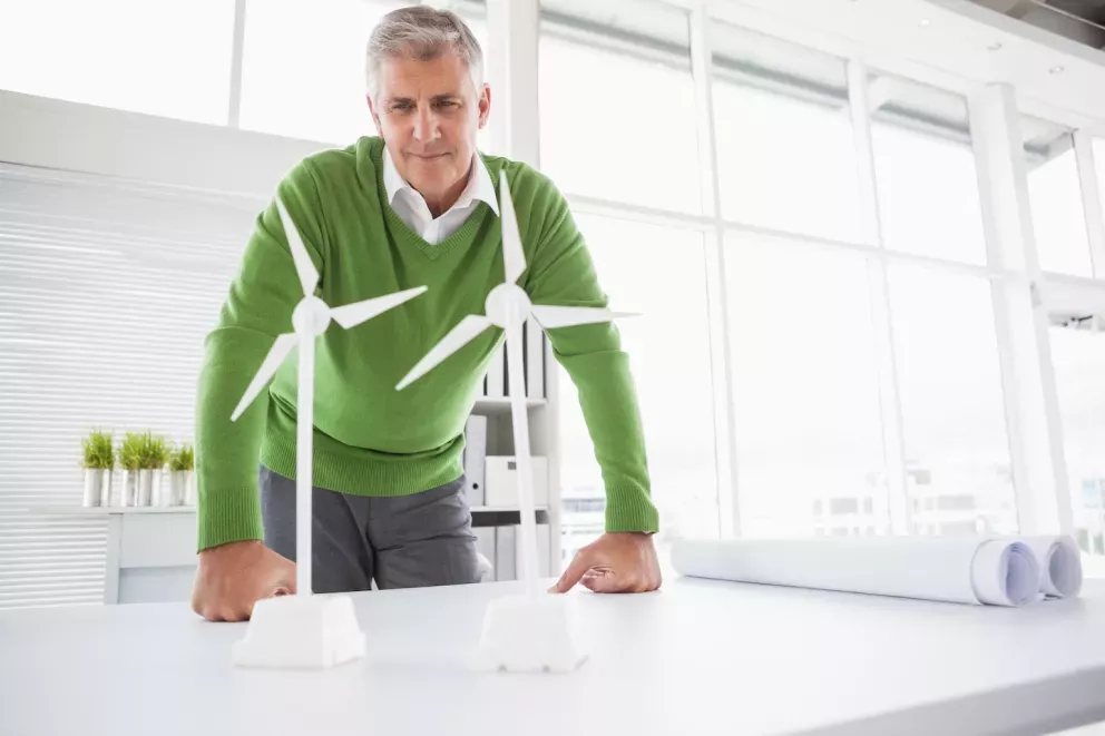 man looking at wind turbine models on his desk man looking at wind turbine models on his desk