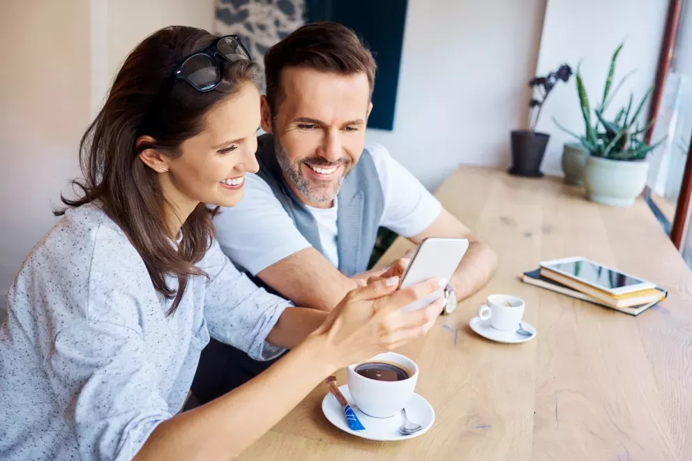 man and woman smiling while looking at phone man and woman smiling while looking at phone