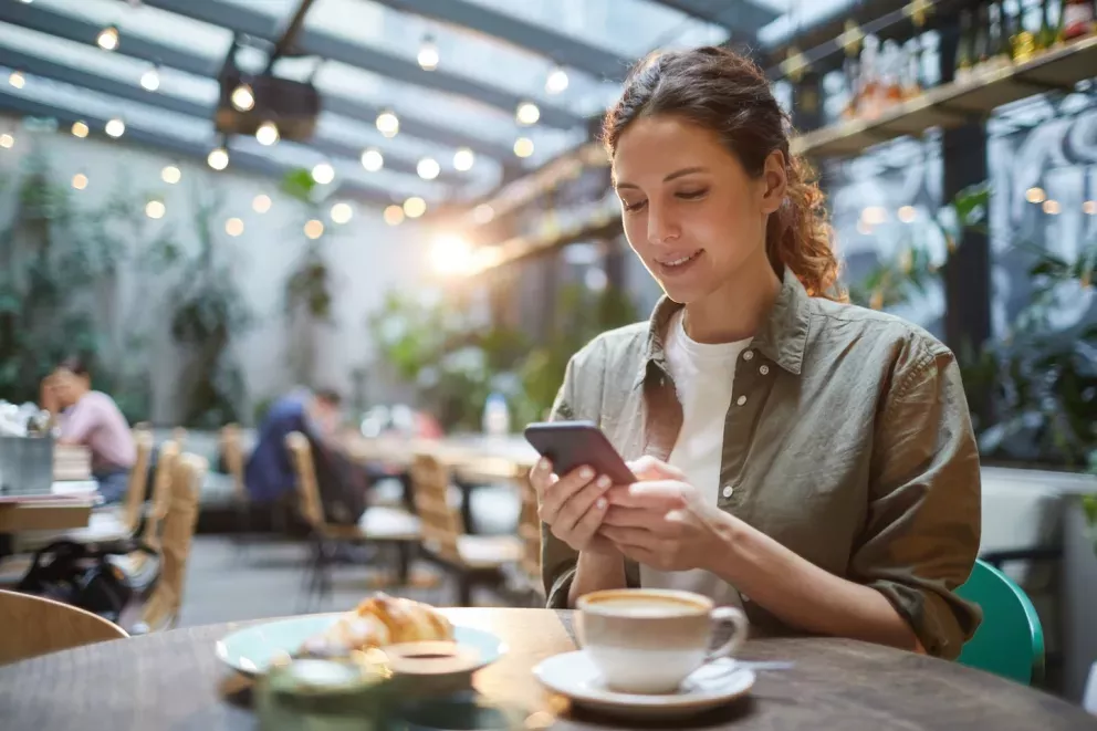 woman looking at phone at coffee shop
