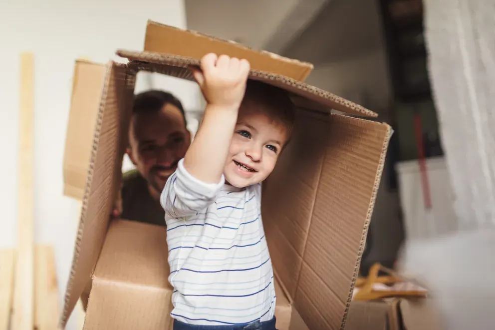 Young boy in cardboard box playing with father Young boy in cardboard box playing with father