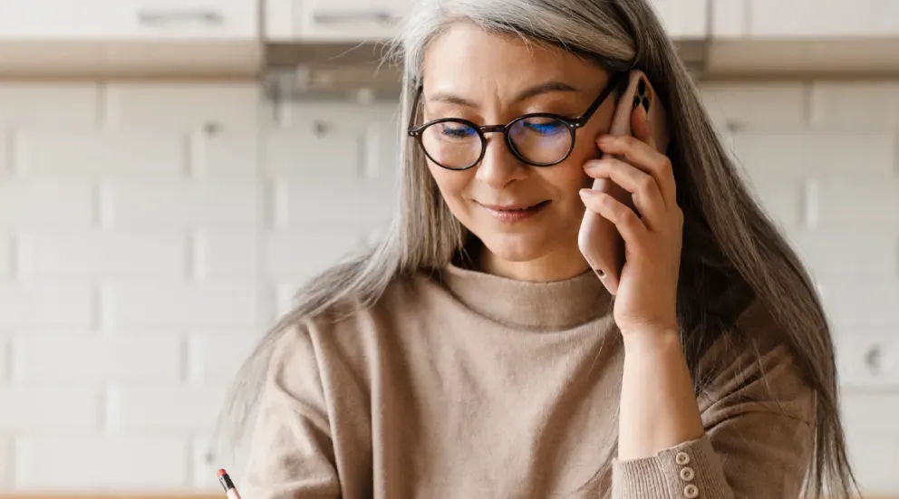 Woman in a sweater and glasses speaking on her mobile phone