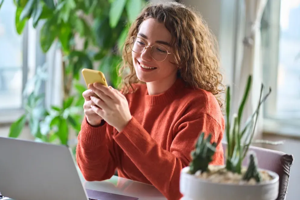 Woman on computer with phone Woman on computer with phone