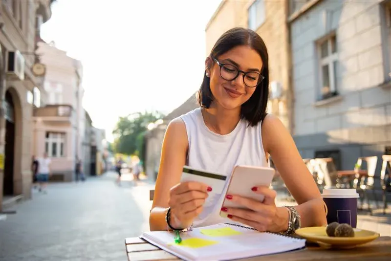 person sitting at table with a phone and credit card
