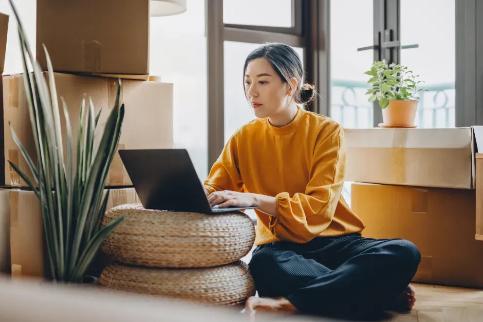 Woman sitting on floor and typing on laptop.