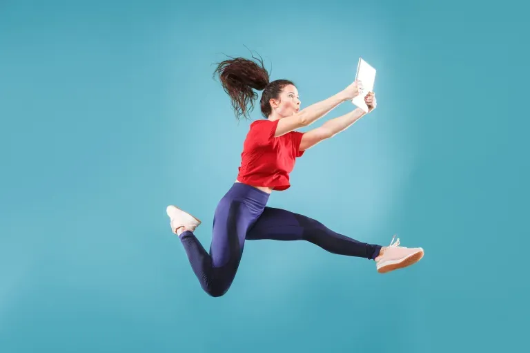 Excited woman jumping with tablet