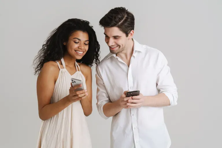Happy young man and woman looking at phones Happy young man and woman looking at phones