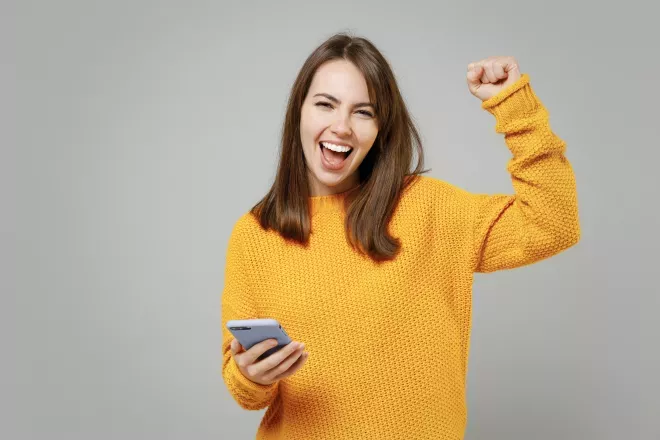 woman holding cell phone exclaiming with happiness woman holding cell phone exclaiming with happiness