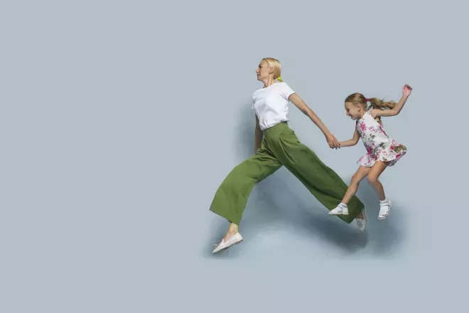 mother and daughter holding hands leaping