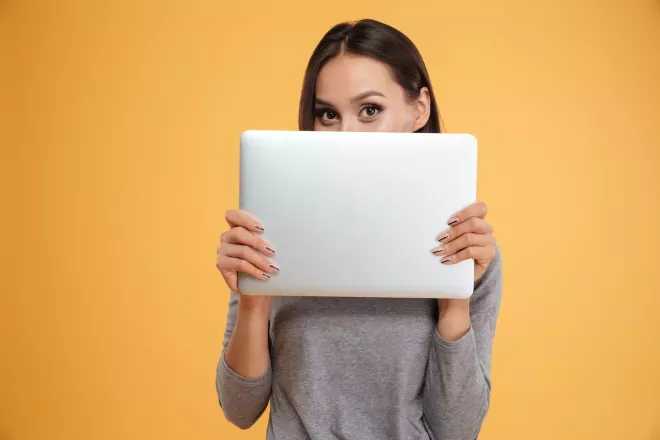 woman holding laptop in front of face