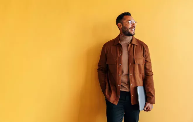 smiling man holding laptop