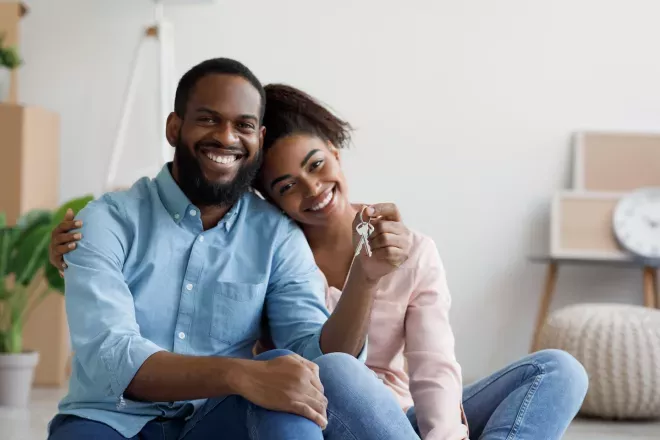 Smiling couple holding up keys to new home 