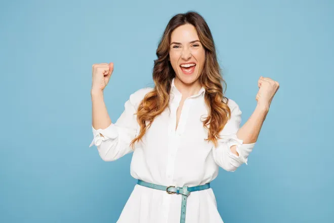 Excited woman white top with fists in air