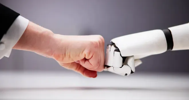 Human hand and white robotic hand reaching toward each other in a handshake gesture.