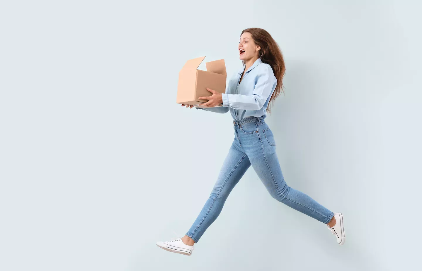 Woman jumping holding a box